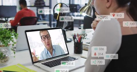 Remote team collaborating on video call with live social notifications in coworking office