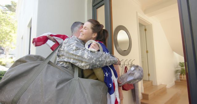 Happy caucasian woman with flag welcoming home male soldier. Military service, returning home, celebration, patriotism and family, unaltered.