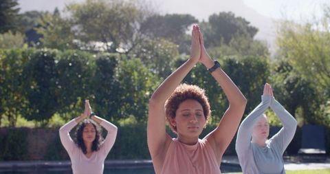 Women Practicing Yoga Outdoors by Pool for Fitness and Relaxation