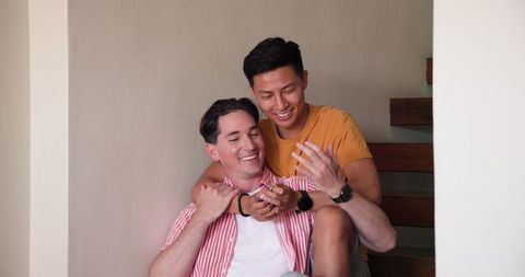 Happy Couple Relaxing on Stairs, Sharing Laughs in Sunny Home