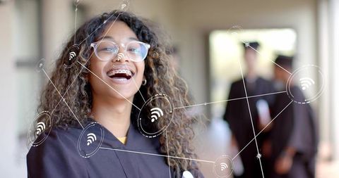 Smiling teenage graduate with braces and glasses connecting on campus using wifi overlay