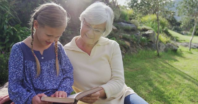 Grandmother Reading Book with Granddaughter in Park - Download Free Stock Images Pikwizard.com