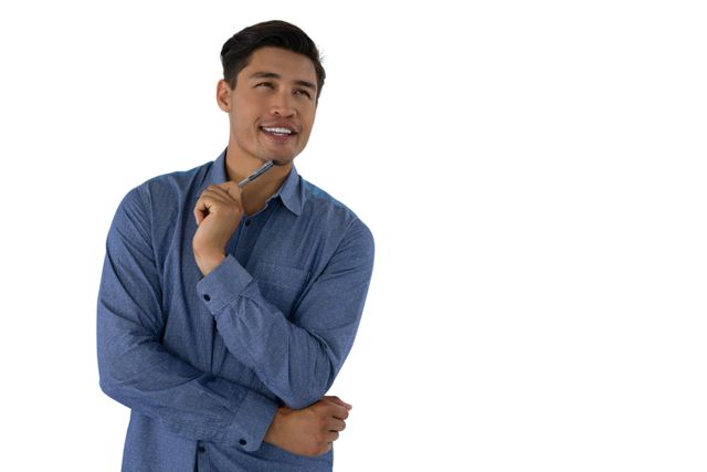 Young businessman in blue shirt holding pen and looking away thoughtfully. Ideal for use in business, decision making, planning, and professional development contexts. Suitable for articles, blogs, and advertisements focusing on business strategies, career growth, and professional advice.