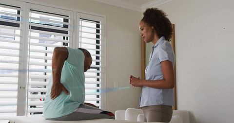 Senior man receiving physiotherapy for lower back pain with attentive clinician