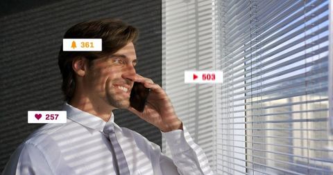 Executive smiling on phone by window blinds with social notifications and sunlit stripes