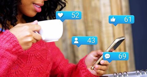 Sipping coffee while checking social media notifications on smartphone cozy knit sweater