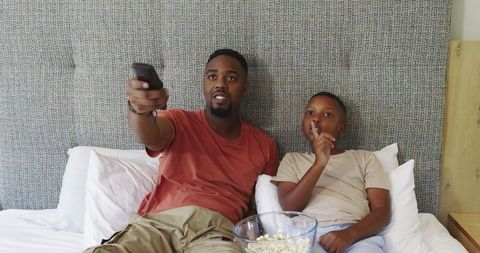 Father and Son Relaxing on Bed Watching Television