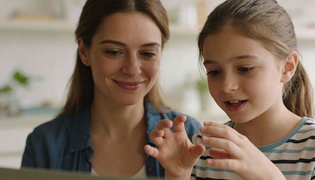 Mother and daughter sharing joyful learning moment using tablet at kitchen counter closeup