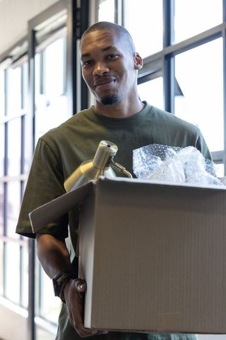 African american man unpacking brass lamp in modern sunlit loft apartment