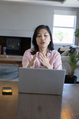 Asian woman engaging in virtual communication at home workspace