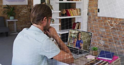 Mid-adult man attending virtual math tutoring on laptop in contemporary loft home office