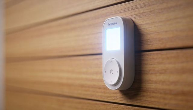 Backlit smart thermostat mounted on wood paneling with blue led display and minimalist design