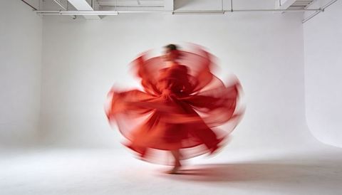Dancer spinning in red dress creating floral motion blur in minimal white studio