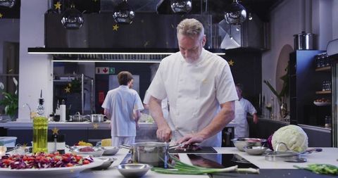 Head Chef Chopping Fresh Produce at Stainless Prep Island in Modern Professional Kitchen