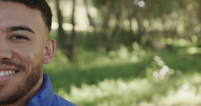 Happy biracial man face close up in sunny forest. Nature, outdoor lifestyle, free time and exploration, unaltered.