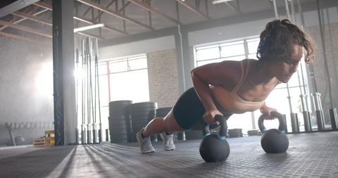 Woman Performing Kettlebell Push-Ups in Industrial Gym