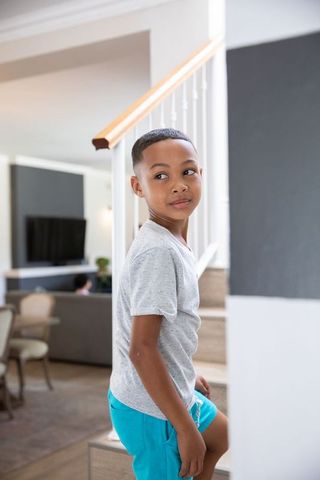 School-age Boy Climbing Home Staircase with Leisurely Glance