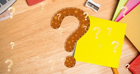 Question marks with school supplies on wooden desk