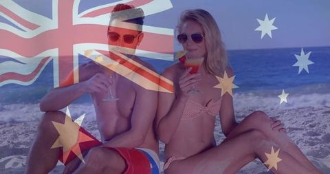 Couple relaxing on australian beach sipping cocktails with flag overlay and sunglasses