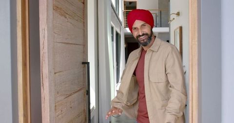 Welcoming man in turban greeting guests at home entrance