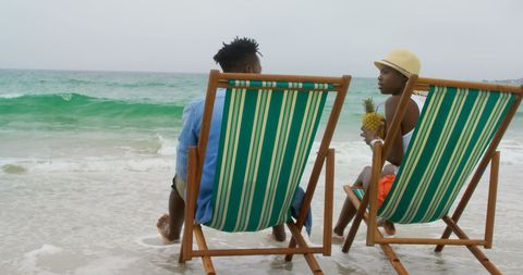 Relaxed african american couple sitting by oceanside
