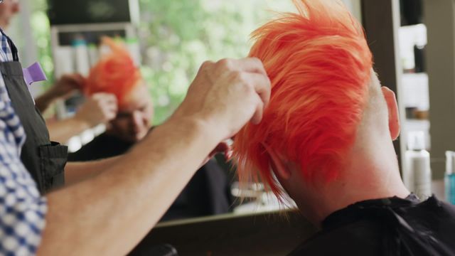 Hairdresser styling bright red hair of female client at salon. Useful for promoting hair salons, styling techniques, beauty services, and hairstylist portfolios. Ideal for ads, brochures, websites, and blog posts about hair care, fashion, and bold hair color trends.