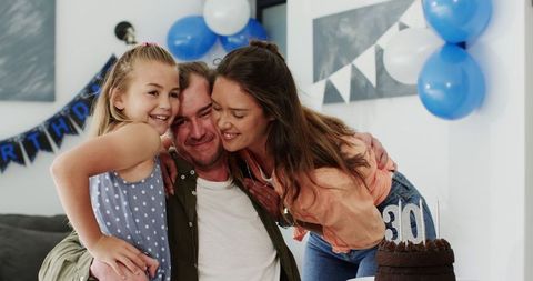 Family Celebrating Father's Birthday Blowing Candles on Cake