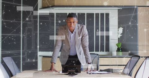 Business executive leaning over conference table reviewing digital briefing