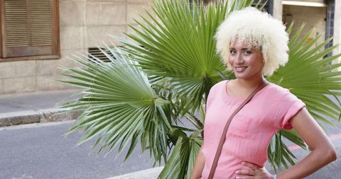 Woman with Curly Blonde Hair Smiling on Urban Street