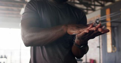 Athlete rubbing chalk on hands in gym