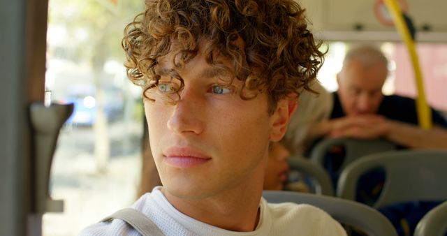 Curly-haired man gazing through bus window on daytime - Download Free Stock Images Pikwizard.com