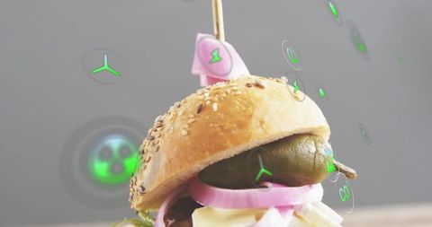 Displaying seeded slider topped with pickle, red onion, cheese and pink flag with ar icons
