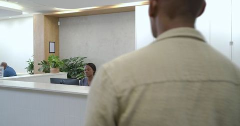 African American Man Talking to Receptionist at Modern Minimalist Office Lobby