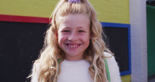 Portrait of happy caucasian schoolgirl looking at camera at school playground. Education, school and learning concept.