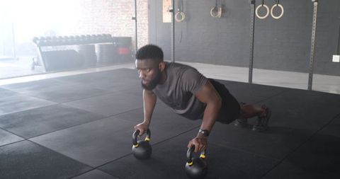 Focused Athlete Performing Push-ups on Kettlebells in Modern Gym