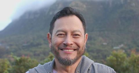 Smiling man on misty mountain with grey hoodie