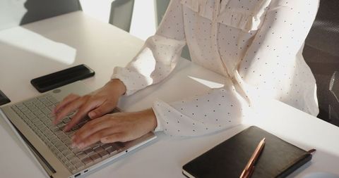 Professional Woman Typing on Laptop in Modern Office Setting