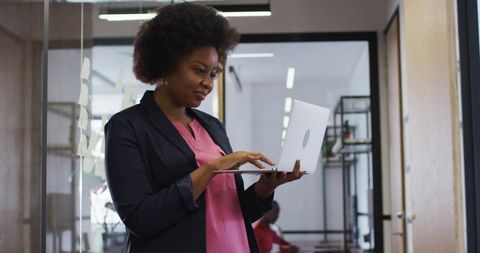 Businesswoman Typing on Laptop in Modern Office Corridor