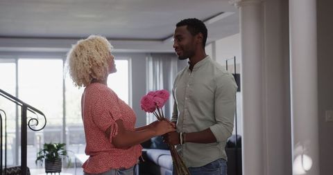 Man Giving Pink Flowers to Friend at Home Embracing Friendship
