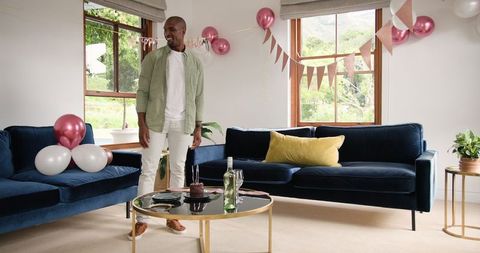 Man Preparing Living Room for House Celebration Party with Balloons and Cake