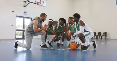 Basketball coach motivating team on indoor court