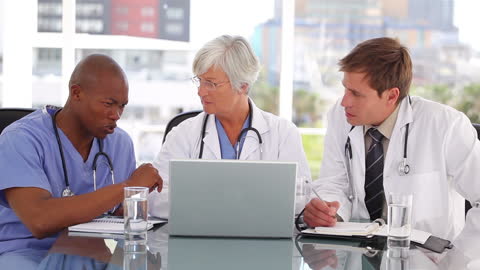 Medical Team Collaborating Over a Laptop in Bright Office