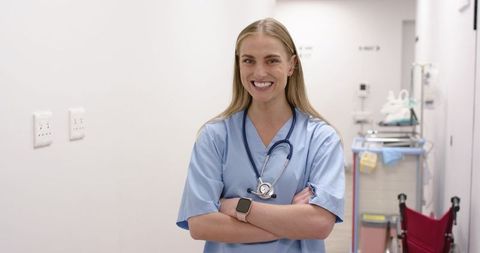 Smiling female nurse standing in bright clinic corridor wearing stethoscope and smartwatch