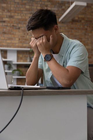 Stressed young man overburdened with workplace challenges in office