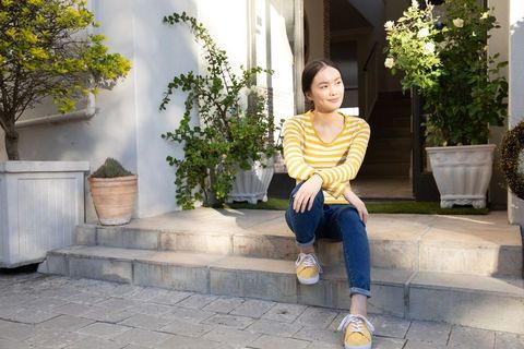Asian Woman Relaxing on Porch Steps Surrounded by Potted Plants