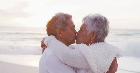 Elderly Couple Kissing on Beach at Sunset