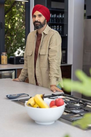 Indian man in modern kitchen with turban and fruit bowl