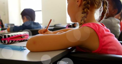 Young Girl in Classroom Writing in Wheelchair
