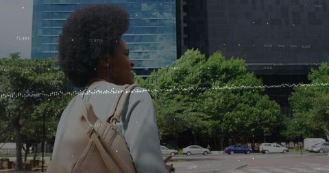 Urban commuter walking with backpack past downtown plaza with digital data overlay