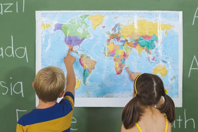 Two school children are pointing at a world map in a classroom, engaging in a geography lesson. This image is ideal for educational content, school brochures, geography learning materials, and back-to-school promotions. It highlights the importance of global awareness and interactive learning in early education.